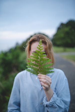 Woman holding fern leaf outdoors