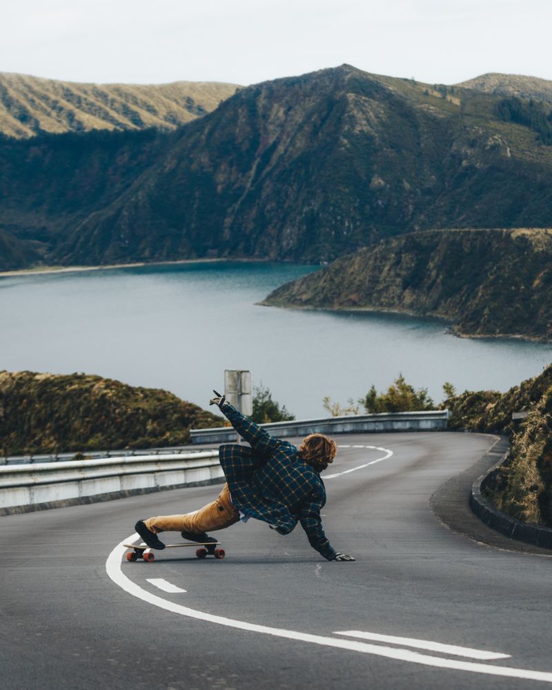 Person roller skating on road near lake and mountain