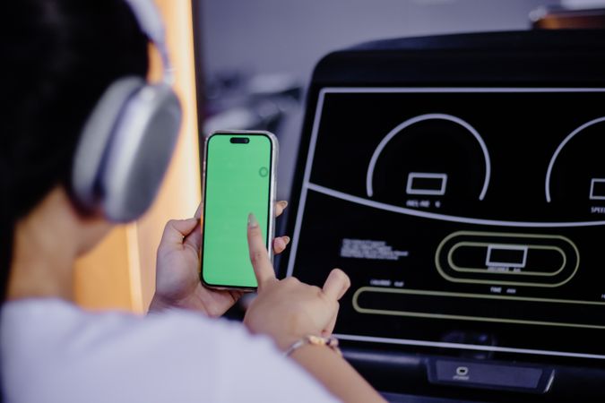Woman Using Phone with Green Screen on Treadmill for Fitness App