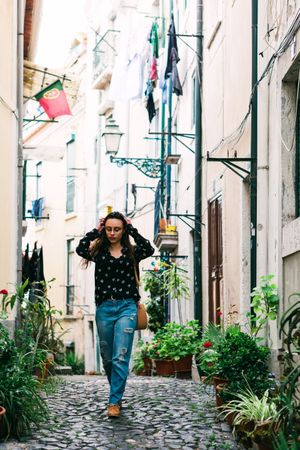 Young casual brunette walking on cobblestone street of old city