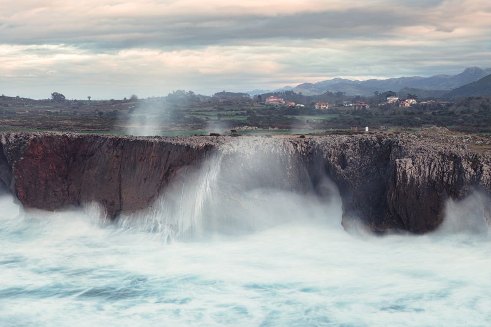Powerful wave splashing at granite cliff