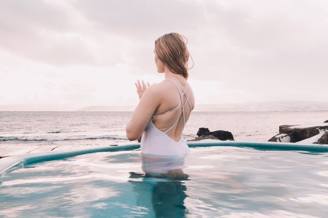 Woman sitting in pool near stones