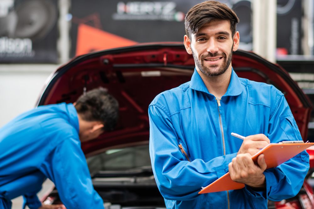 Portrait of automotive mechanic man writing on maintenance document clipboard