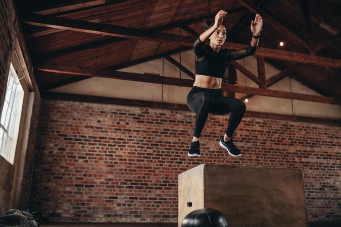 Fitness woman doing box jump workout at gym