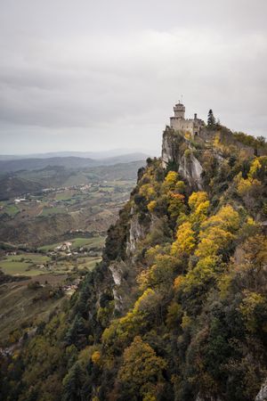 Stone peak with castle overgrown with trees and bushes rush into sky
