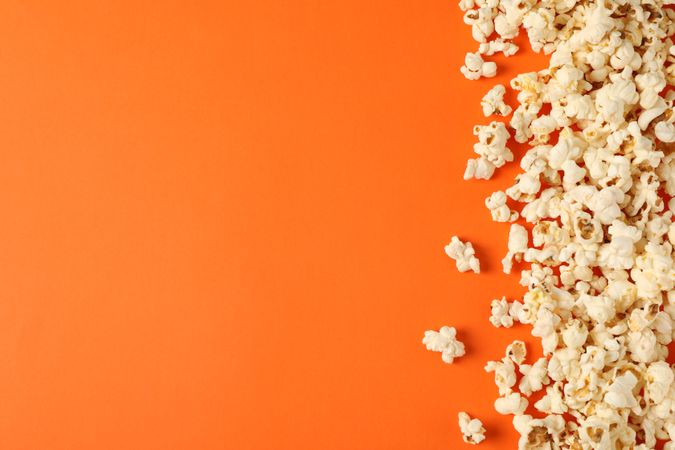Flat lay composition with popcorn on orange background, copy space