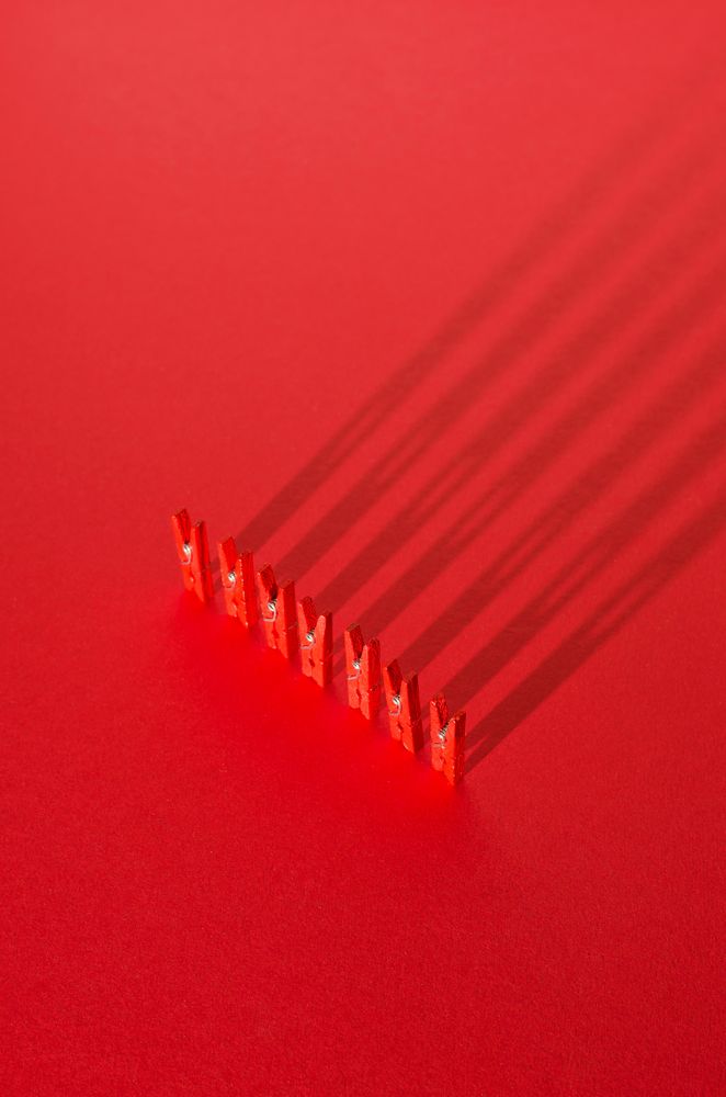 Red clothes pins on red background