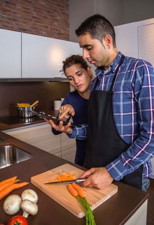 Couple checking digital tablet for instruction while prepping dinner