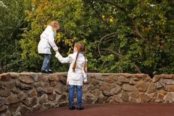 Girl helping her sister balance on wall