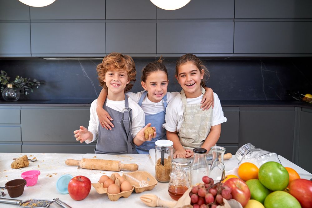 Cheerful children with dough in kitchen