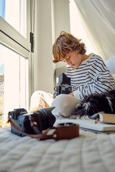 Boy with retro photo camera and purebred dog on bed