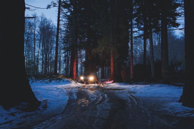 Car riding along dirty road in evening forest