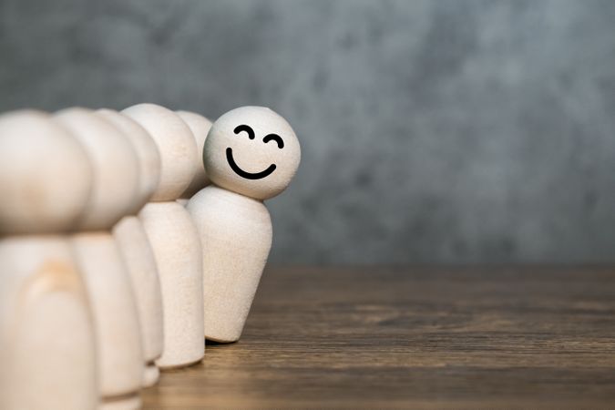 one wooden figure feel happy from the crowd. leadership and differentiation concept