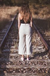 Long haired woman standing on railways overgrown with dry grass