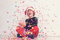 Smiling boy in Santa hat under colorful confetti