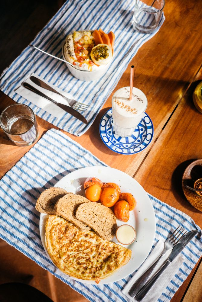 Table set with omelette breakfast and bowl of fresh fruit and yogurt