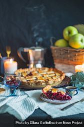 Sweet baked pie with fruit filling on table with basket of apples bGq125