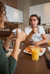Couple talking while eating pastries and drinking coffee at breakfast