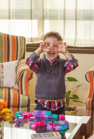 Funny kid making monster face and playing in home