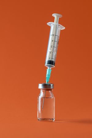 Vaccine vial with syringe isolated on an orange background