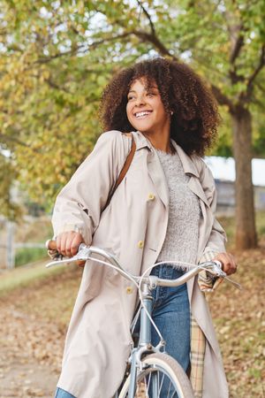 Smiling Black woman with bicycle in park
