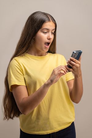 Shocked young woman reacting to unbelievable content on her smartphone.