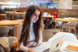 Brunette woman in a restaurant day dreaming on her laptop