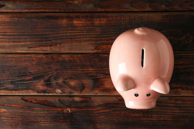 Happy piggy bank on wooden background, space for text and top view. Finance, saving money