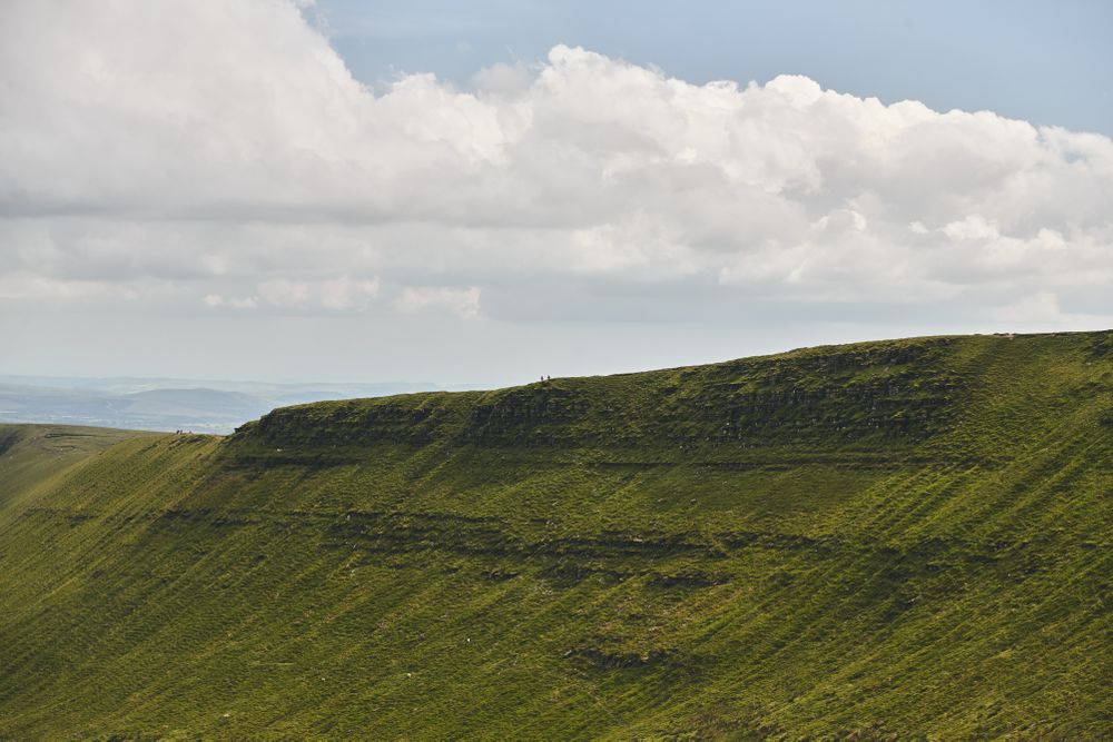 Brecon Beacons mountain range on a cloudy day with people in the distance