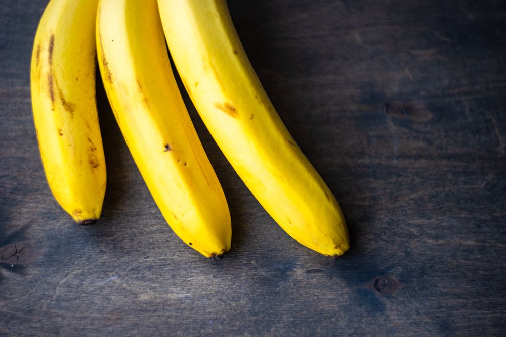 Three tasty bananas on wooden background
