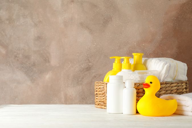 Baby hygiene accessories on wooden table against brown background