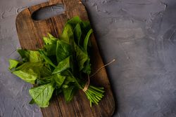 Looking down at fresh spinach wrapped on board
