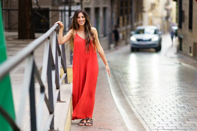 A charming woman in a vibrant red dress strolls gracefully through a scenic European street