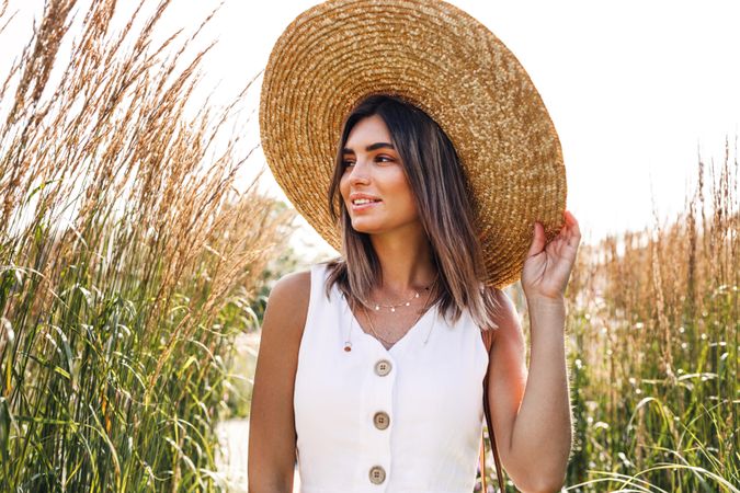 Calm happy woman in a field outside wearing a sunhat