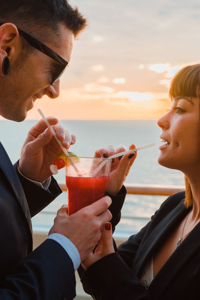 Young man and woman drinking juice from one glass