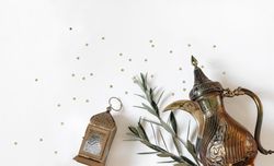 Arabic dallah coffee pot, golden ornamental Moroccan lantern and green olive tree branches