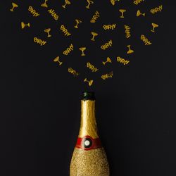 Golden champagne party bottle on background with gold confetti