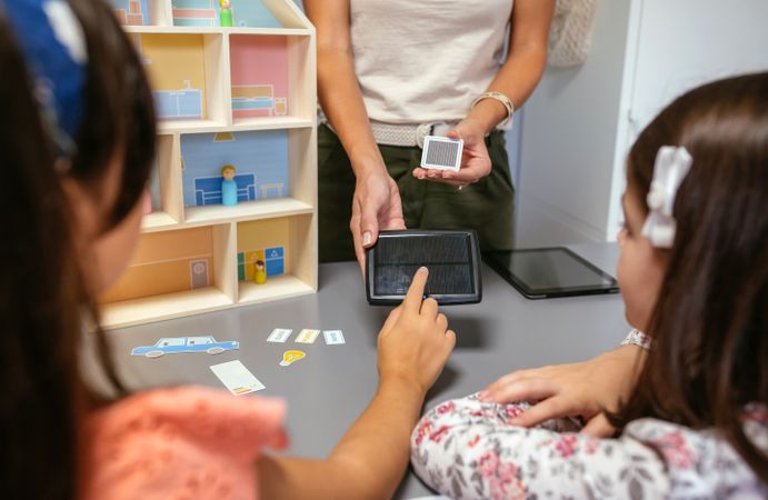 Unrecognizable teacher explaining to her students the parts of a sustainable house showing a solar panel