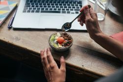 Person with fruit bowl in front of laptop