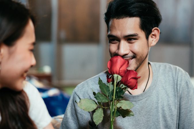 Asian man smelling rose for his girlfriend on date