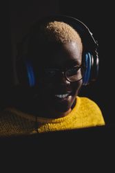 Smiling Black woman in headphones in dark room