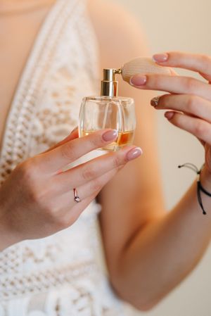 Woman in light lace dress spraying perfume