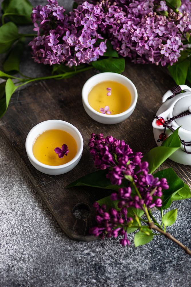 Board with two cups of tea & lilac flowers