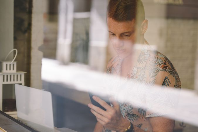 Man talking on smartphone while browsing laptop
