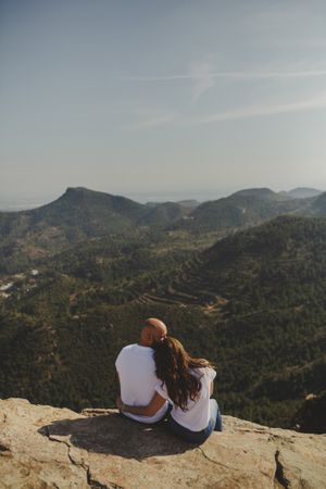 Happy couple sitting at mountain cliff