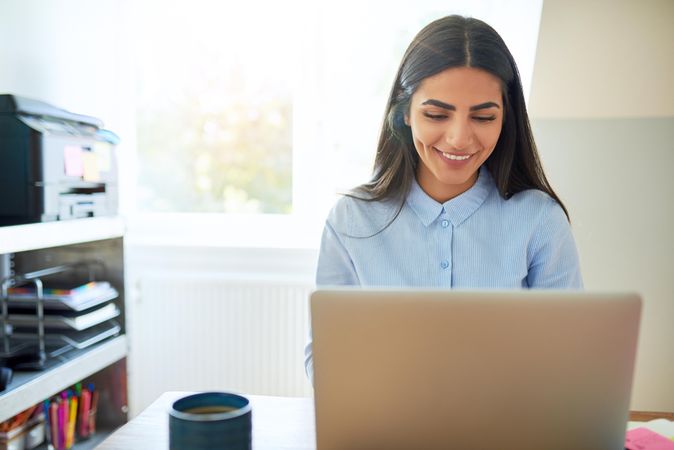 Happy woman using laptop in bright office