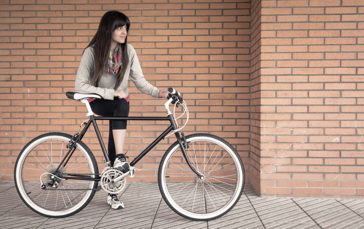 Sportive woman with fixie bike over a brick wall