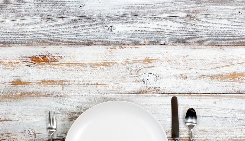 Top view of clean dinner plate and silverware on rustic table