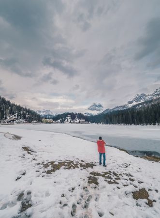 Unrecognizable person standing in snow surrounded by forest and mountains
