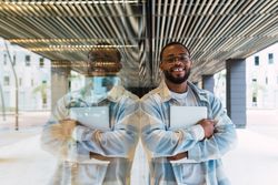 Joyful Black man with laptop near building